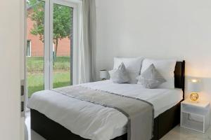a bedroom with a large white bed with a window at Gemütliche Wohnung mit Terrasse im Grünen in Bienenbüttel
