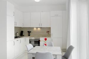 a white kitchen with a table with a red flower on it at Gemütliche Wohnung mit Terrasse im Grünen in Bienenbüttel