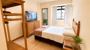 a bedroom with a bed and a television in it at No centro da cidade 750m da universidade in Viçosa