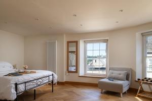 a bedroom with a bed and a chair and a window at Tranquility House in Painswick