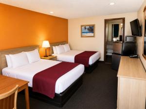 a hotel room with two beds and a flat screen tv at Sunrise Inn - Bradenton in Bradenton