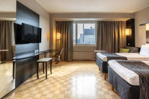 a hotel room with two beds and a flat screen tv at Scandic Tampere Hämeenpuisto in Tampere