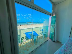a room with a balcony with a view of the beach at Suítes Pitangueiras - POUSADA FRENTE MAR in Guarujá