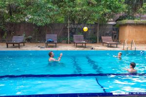 three people playing with a ball in a swimming pool at A4 By Gabaa in Habarana