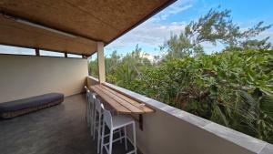 a balcony with a wooden bench and some plants at Le chant des vagues in Saint-Philippe
