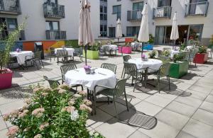 a patio with tables and chairs with umbrellas and flowers at Hotel Kolping Wien Zentral in Vienna