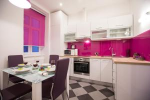 a kitchen with pink walls and a table and chairs at Apartment Center Four stars in Zagreb
