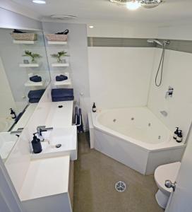 a white bathroom with a tub and a sink at Apollo Bay Waterfront Motor Inn in Apollo Bay +47 photos