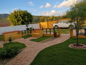 a park with a bench and a fence and a car at Florida Palace Hostal in Samaipata