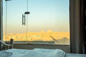 a bedroom with a view of the pyramids from a window at Pyramita luxury hotel in ‘Ezbet `Abd el-Ḥamîd