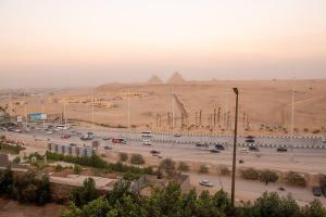 a parking lot in the desert with pyramids in the background at Pyramita luxury hotel in ‘Ezbet `Abd el-Ḥamîd