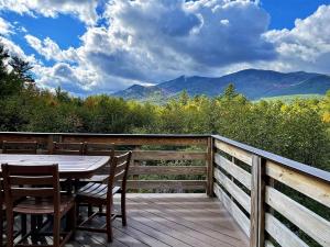 a table and chairs on a deck with a view of mountains at Stunning Views, Luxury, Near Whiteface,Lake Placid in Wilmington