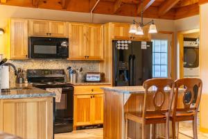 a kitchen with wooden cabinets and a black refrigerator at Mountain Home, Views, Near Whiteface, Lake Placid in Wilmington