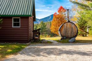 a cabin with a barrel next to a building at Mountain Home, Views, Near Whiteface, Lake Placid in Wilmington