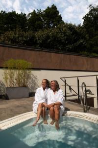two people in white robes sitting next to a swimming pool at Landgoed Duin & Kruidberg in Santpoort-Noord