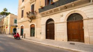 a red scooter parked next to a building with brown doors at The Suite - Trani centro in Trani