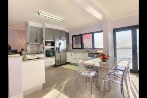 a kitchen with white cabinets and a table with chairs at Villa do Paul by LovelyStay in Paul do Mar