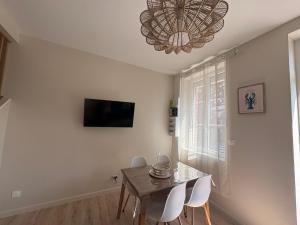 a dining room with a table and chairs and a chandelier at Le Petit Bleu - Charming House in Yport +6 photos