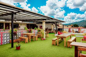 a patio with wooden tables and benches on the grass at Che San Cristobal de las Casas Hostel in San Cristóbal de Las Casas