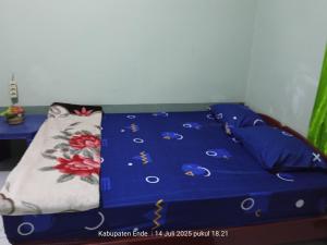 a bed with a blue comforter and pillows on it at Kelimutu Lodge in Kelimutu