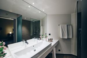 a bathroom with a white sink and a large mirror at Hôtel des Voyageurs Boutique in Lausanne