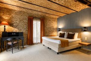 a bedroom with a bed and a desk and a brick wall at Hotel Winselerhof by Flow in Landgraaf