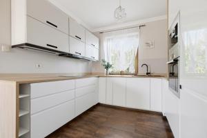 a kitchen with white cabinets and a wooden floor at Biały Dom in Gdańsk