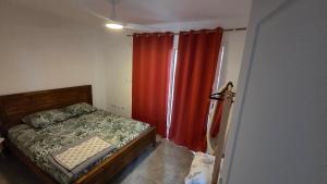 a bedroom with a bed and a red curtain at le Chant des vagues 1 in Saint-Philippe