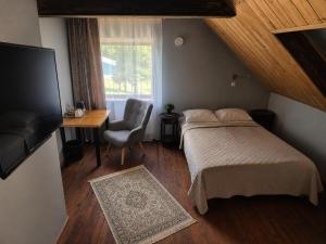 a bedroom with a bed and a chair and a window at Kütioru puhkekeskus in Koloreino