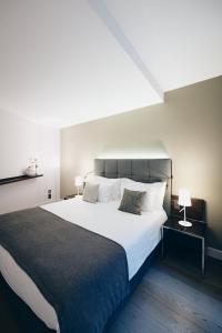 a bedroom with a large white bed and two lamps at Hôtel des Voyageurs Boutique in Lausanne