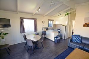 a living room with a table and chairs and a kitchen at Apollo Bay Waterfront Motor Inn in Apollo Bay