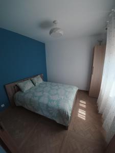 a bedroom with a bed and a blue wall at Cosy et Calme in Cholet