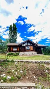a log cabin with a blue sky and clouds at El Rancho in Villa Giardino