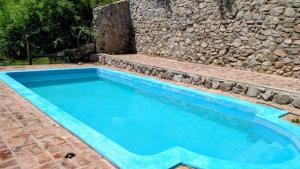 a swimming pool in front of a stone wall at El Rancho in Villa Giardino