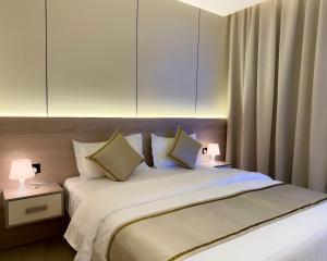 a bedroom with a large white bed with two lamps at أجنحة كتارا صلالة Katara Suites Salalah in Salalah