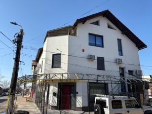 a white building with a car parked in front of it at Zen Rooms in Suceava
