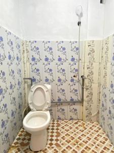 a bathroom with a toilet with blue and white tiles at Surak Villa Mentawai in Katiet