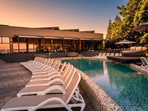 a row of lounge chairs next to a swimming pool at Premium Hotel Panoráma in Siófok