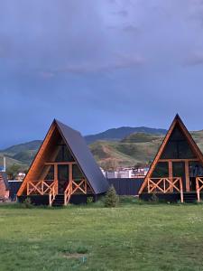a couple of large wooden buildings in a field at Kolsay Aframe Vibes in Saty