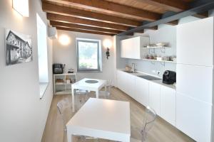 a kitchen with white cabinets and a white table at Alla Corte del Gallo in Tricesimo