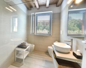 a bathroom with a sink and a toilet and two windows at Alla Corte del Gallo in Tricesimo +18 photos