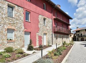 a red building with a balcony next to a street at Alla Corte del Gallo in Tricesimo