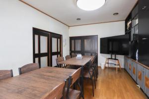a dining room with two tables and a flat screen tv at 民泊 Vacation rental "Tajimi-jyuku Kitaya" Base for trips to Ghibli Park,Tsumago-juku,Magome-juku in Tajimi