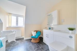 a white bathroom with a sink and a chair at The Donkey Shed in Sherborne +34 photos