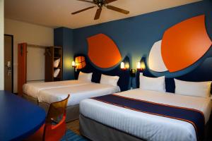 a hotel room with two beds with orange and blue walls at Explorers Hotel Marne-la-Vallée in Magny-le-Hongre