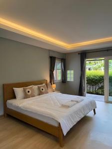 a bedroom with a large bed with a large window at Zerohouse in Ban Bang Bao