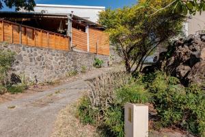 a stone wall next to a road next to a building at KAZUBUNTU in Saint-Leu