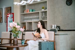 a woman sitting in a chair reading a book with a suitcase at Horizon Minh Chau Hotel in Quang Ninh +83 photos