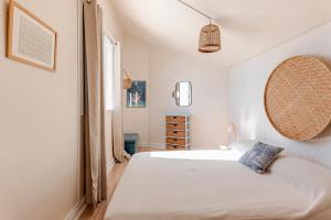 a white bedroom with a bed and a window at KAZUBUNTU in Saint-Leu