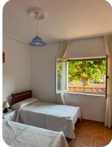 a bedroom with two beds and a window at El Rincón de pedreña in Pedreña